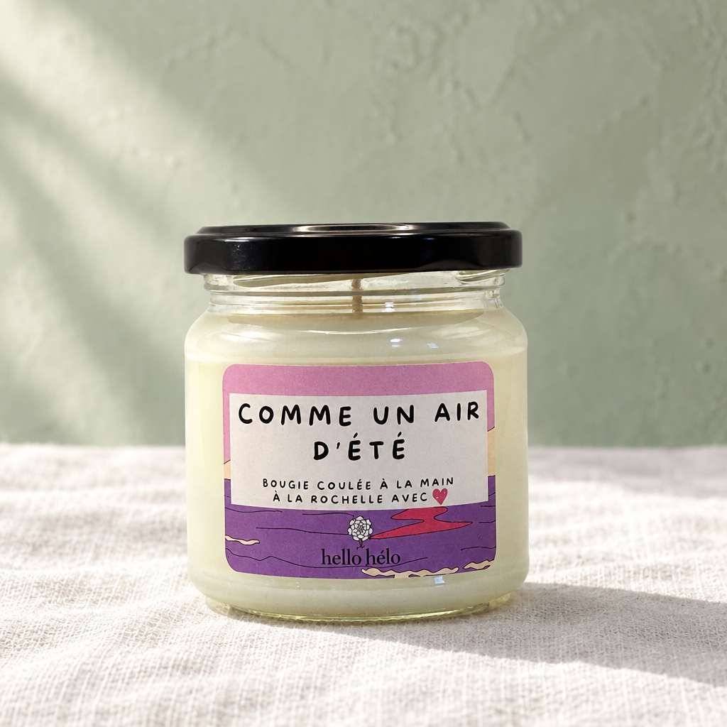 Bougie artisanale Comme un air d'été, pot en verre fermé avec étiquette violette et rose, sur un lin blanc devant un mur vert sauge