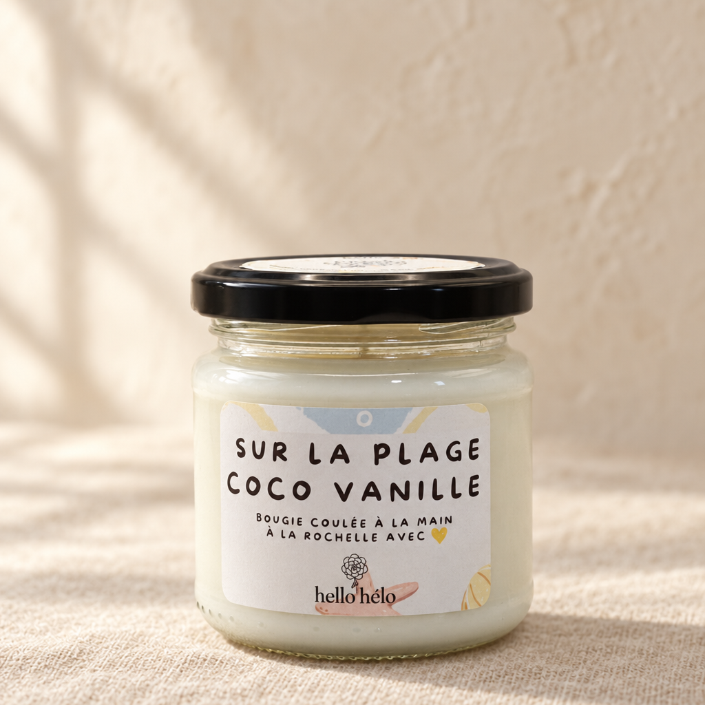 Bougie artisanale Sur la plage coco vanille, pot en verre fermé avec étiquette illustrée, sur un lin beige devant un mur crème éclairé par la fenêtre