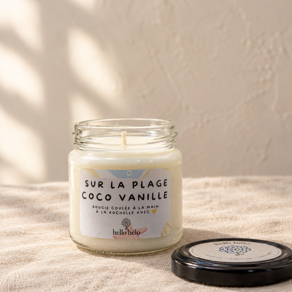 Bougie artisanale Sur la plage coco vanille, pot en verre ouvert avec son couvercle noir posé à côté, sur un lin beige devant un mur crème